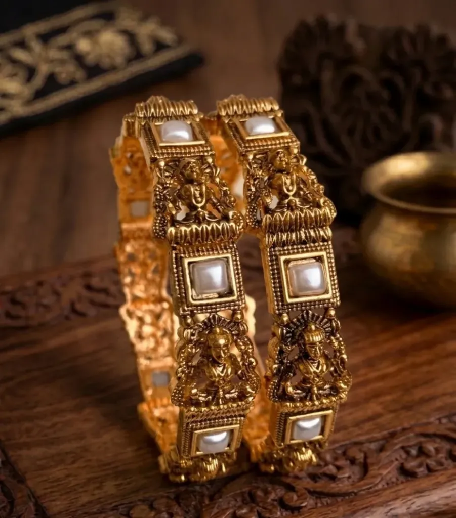 Handcrafted gold toned bangles featuring ornate deity motifs and embedded white stones, celebrating artistry and heritage. (2.4)