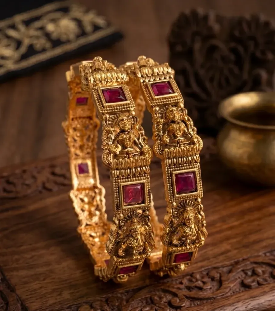 Sacred artistry in gold-toned bangles, embellished with ruby-red stones and mythological detailing.
