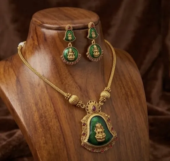 Cool short haram &earrings combo featuring a green enamel pendent with a golden goddess charm and ruby details. Add a pop of traditional flair to your everyday look.