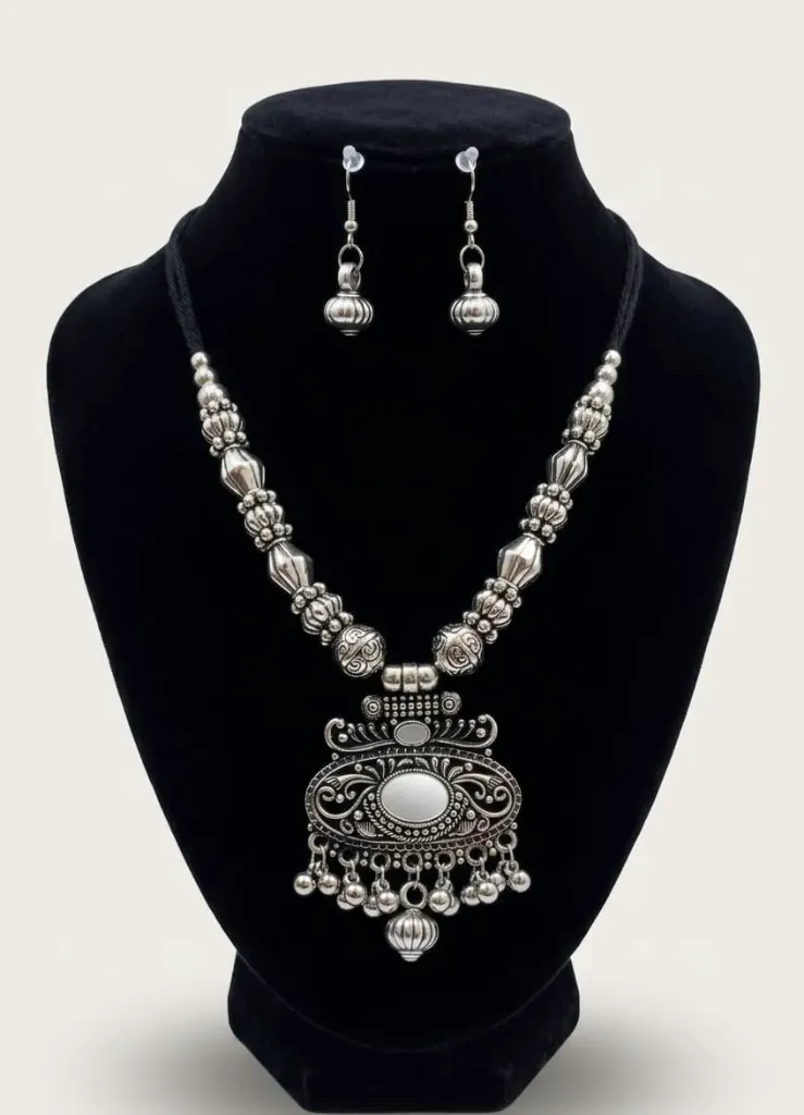 Silver oxidized necklace set with intricate bead chain and large pendent featuring an oval mirror centerpiece, paired with matching earrings.