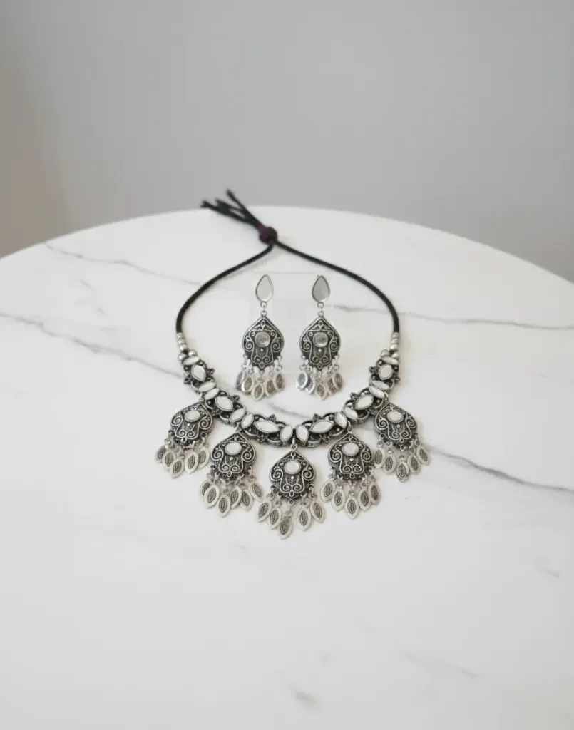 Elegant oxidized  silver chocker necklace paired with matching earrings featuring detailed scrollwork and pearl like stone embellishment, ideal for ethnic or boho styling.