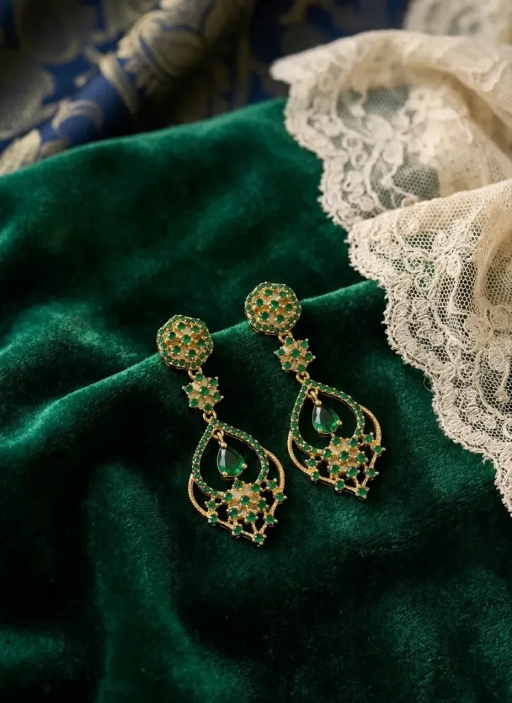 Gold-toned dangler earrings studded with green stones and pearl-shaped centerpiece.