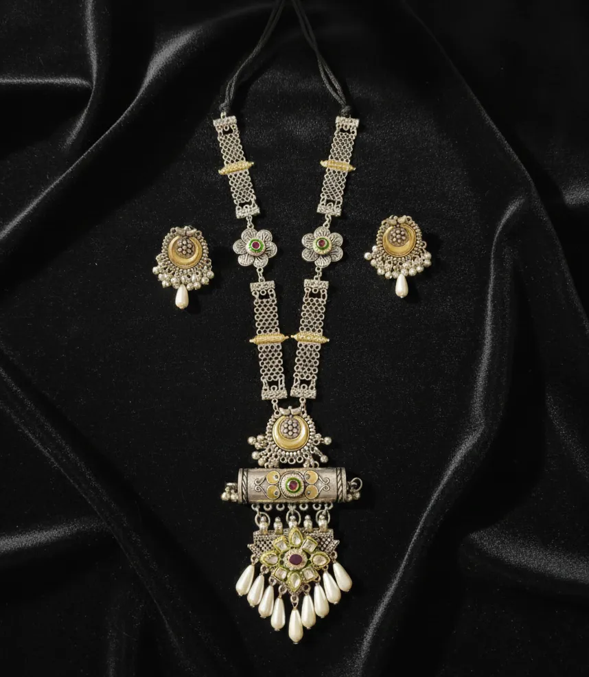 This exquisite oxidized long haram features intricate dual-tone detailing, kundan accents, and elegant pearl droplets for a truly regal look.