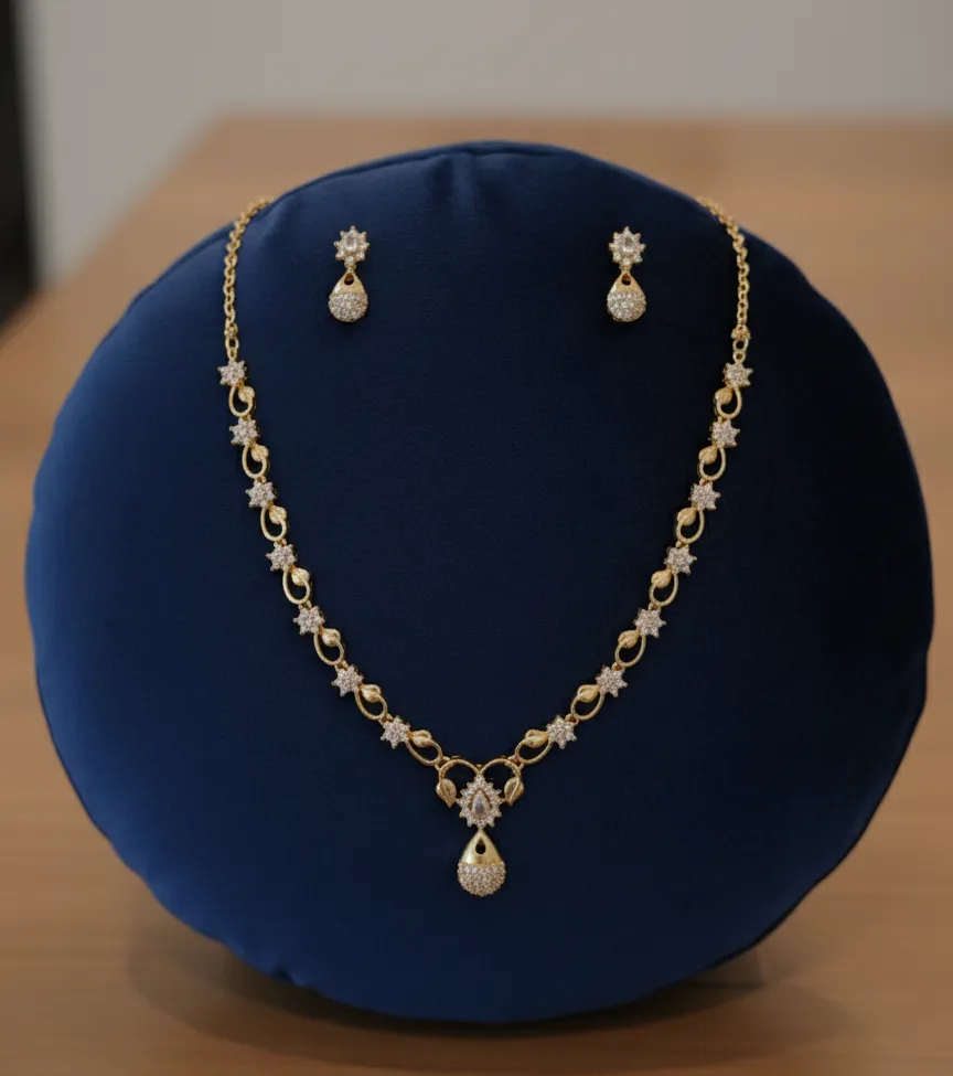 This elegant gold-toned AD necklace set features a Delicate floral-leaf vine design accented with shimmering white stones and a graceful teardrop pendent.