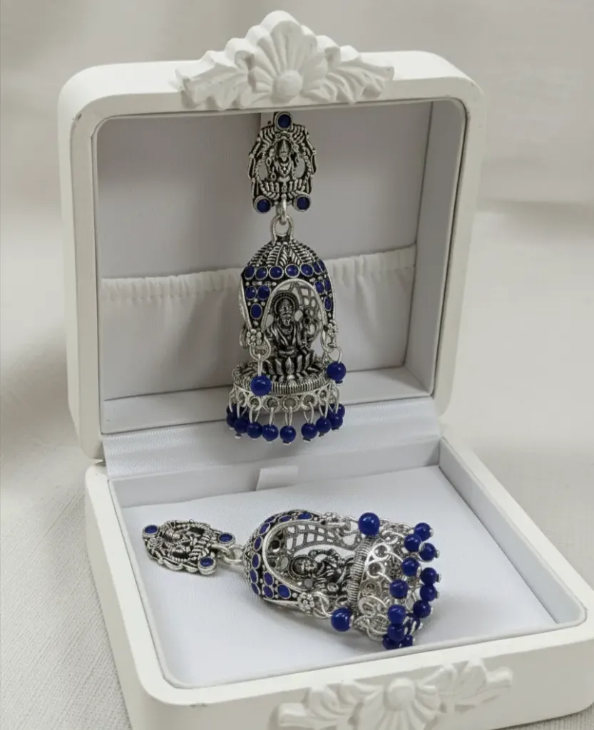Exquisite oxidized silver Jhumkas featuring intricate divine motifs and vibrant cobalt blue bead accents for a vintage charm.