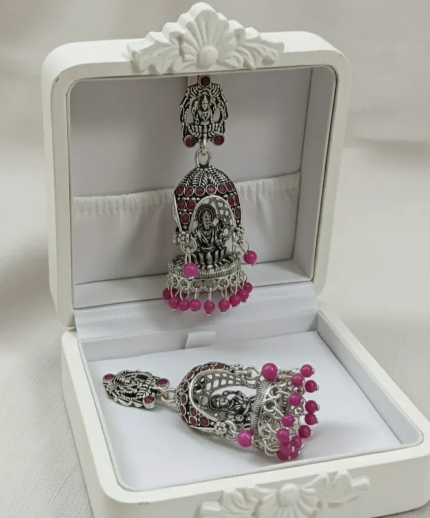 Embrace a classic ethnic look with these oxidized Jhumkas, showcasing intricate Temple art and vibrant pink bead detailing.