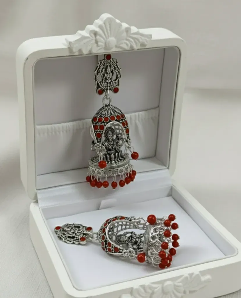 Embrace a classic ethnic look with these oxidized Jhumkas, showcasing intricate Temple art and vibrant red bead detailing.