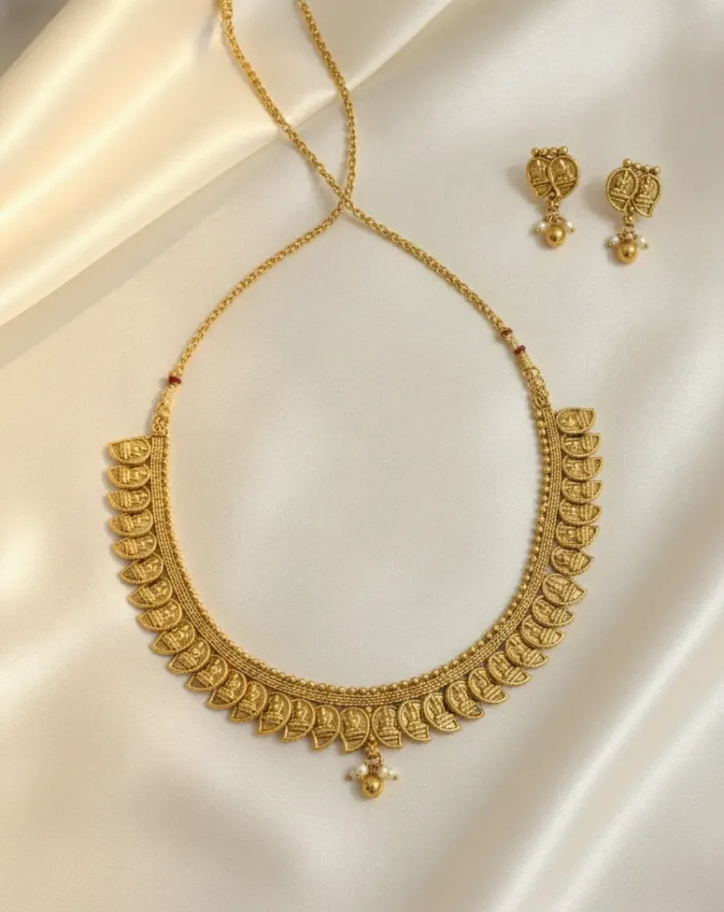 Adorn yourself with the divine grace of this intricately embossed Goddess Lakshmi necklace, featuring a continuous row of sacred motifs and delicate pearl drop accents.