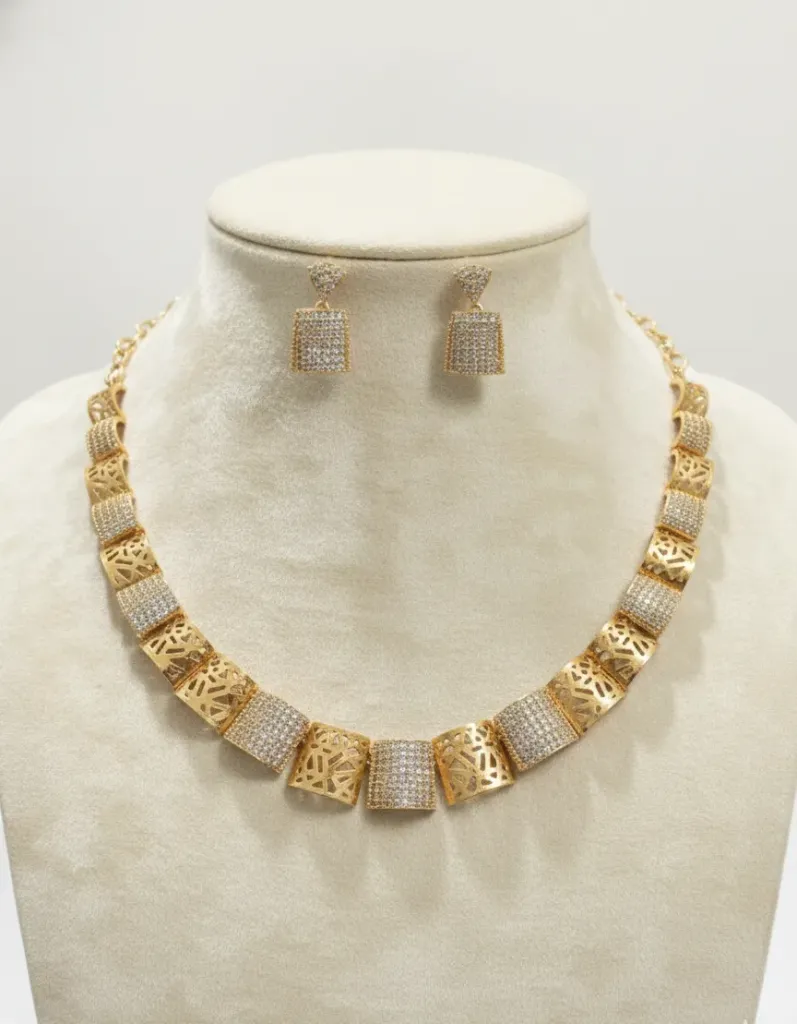 Elevate your style with this Gold-Toned AD Necklace Set, featuring a sophisticated sequence of intricate filigree and shimmering stone-studded panels.