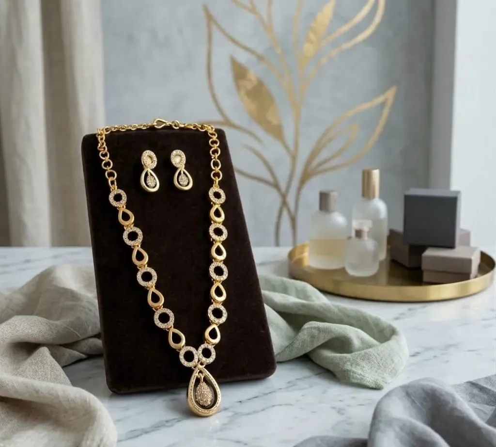 Elegant Gold Necklace with sparkling AD set links and teardrop pendent, paired with matching gold toned earrings.