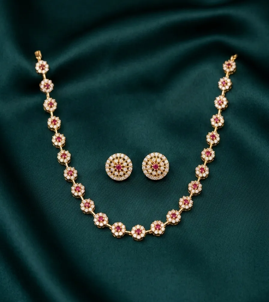 Elegant gold toned necklace and matching earrings set adorned with sparkling white and ruby -red stone flowers.