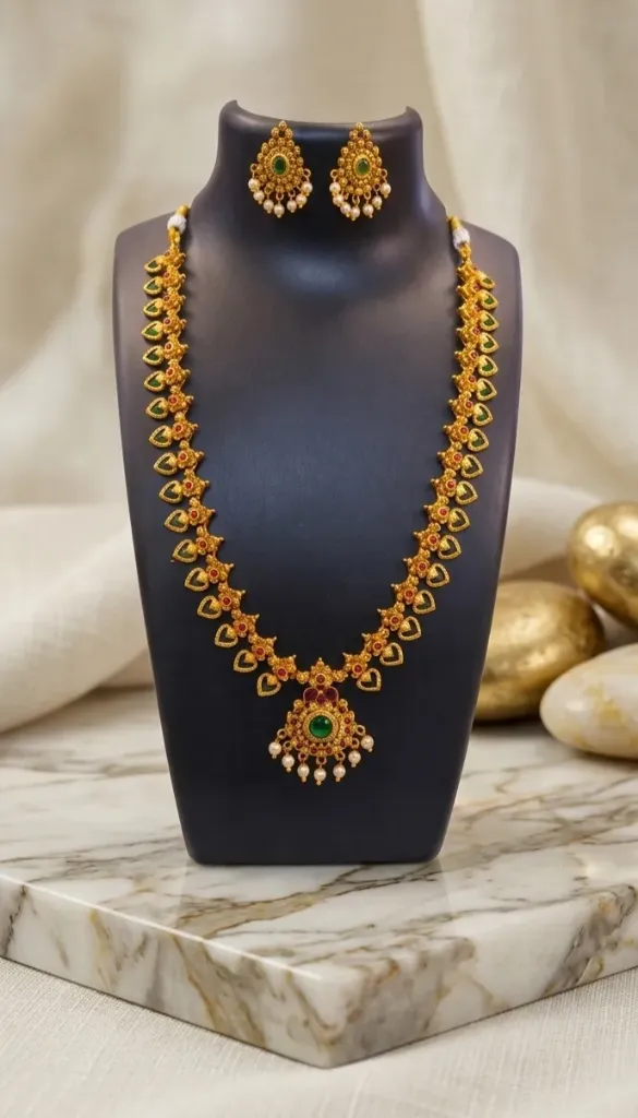 Elegant gold toned necklace set with emerald and ruby accents, pearl detailing, and matching earrings-perfect for festive elegance.