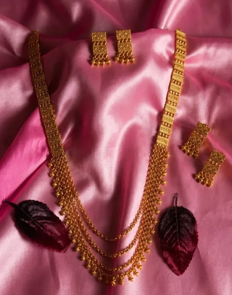 Stunning gold necklace with layered chain detailing and matching rectangular earrings, crafted with intricate patterns and dragline beads for a classic, luxurious look.