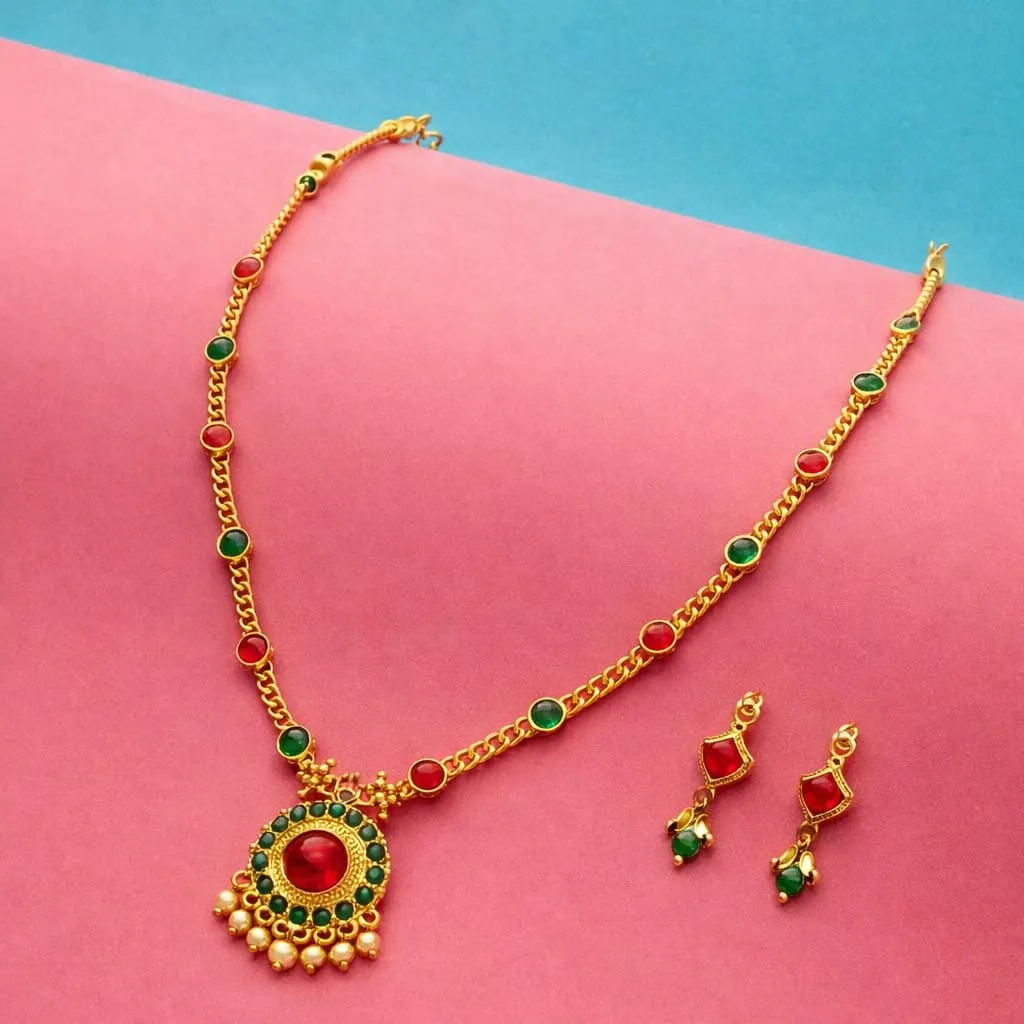 Stunning gold toned necklace set with a vibrant red center stone surrounded by green accents and pearl detailing, paired with matching earrings-perfect for adding a pop of traditional elegance to any outfits.