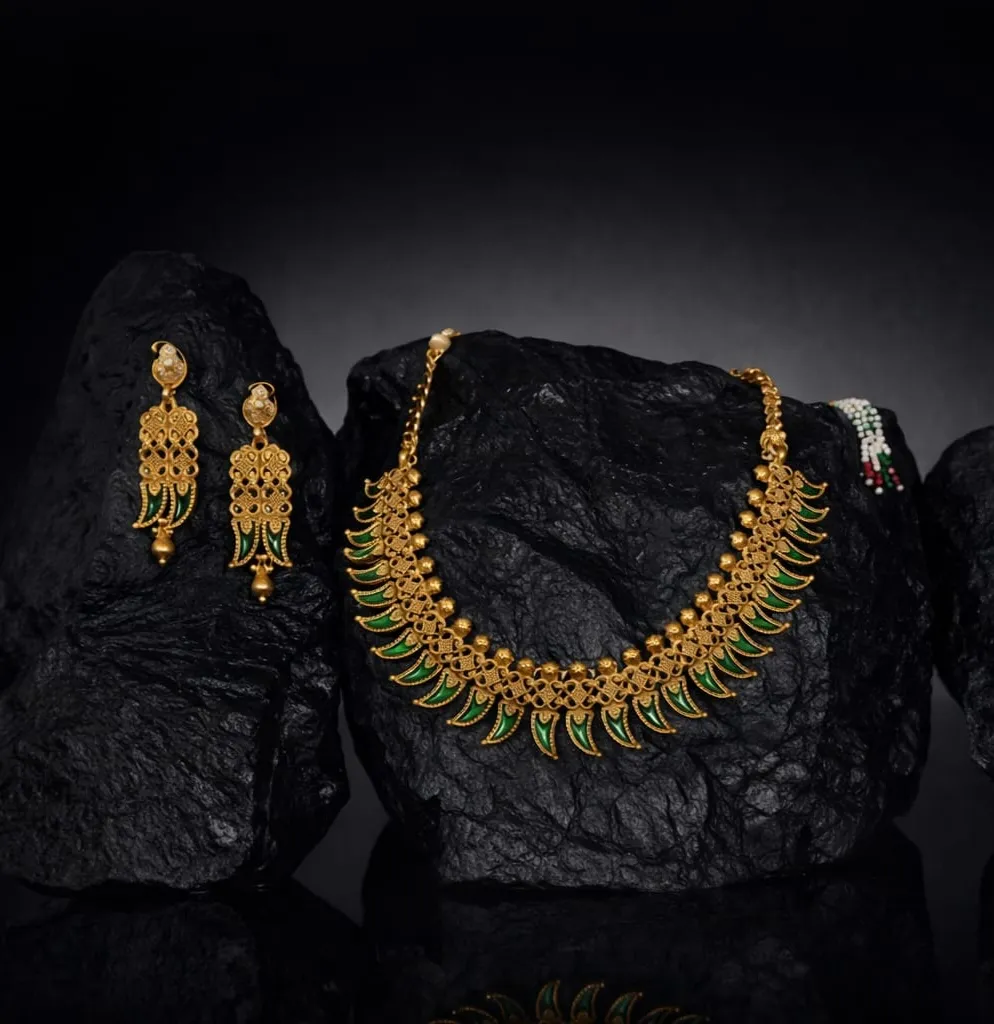 Traditional; elegance meets vibrant flair in this gold necklace and earring set, accented with emerald green enamel and intricate filigree.