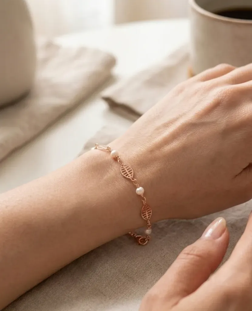 A delicate rose-gold bracelete with leaf-shaped charms and pearl accents.
