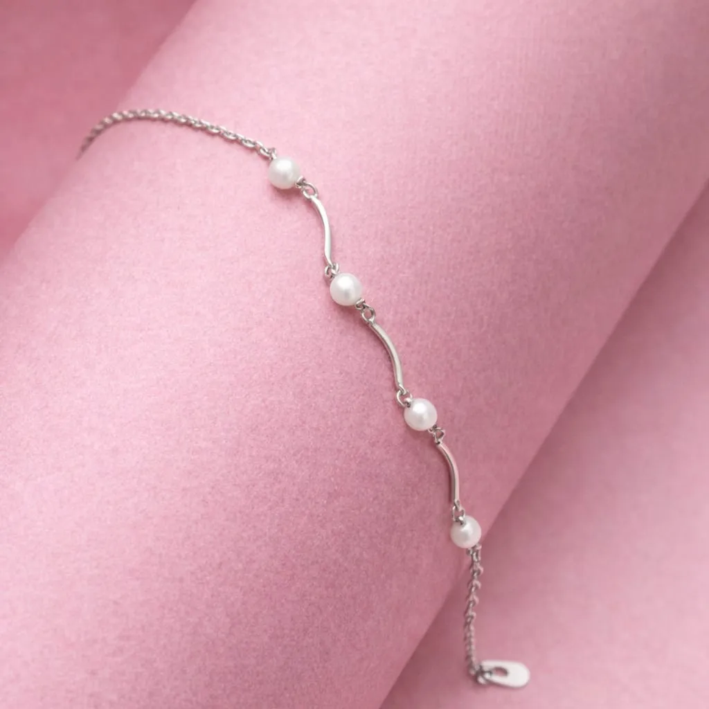 Deliciated silver bracelet with pearl accents spaced along with curved siler bars.