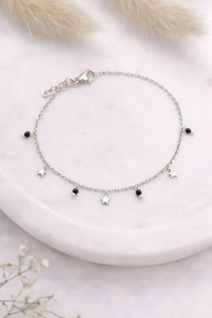 Chic silver chain bracelet adorned with tiny stars charm and black bead accents.